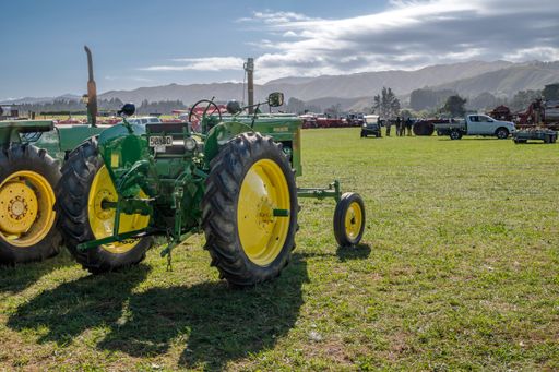 The green tractors in a green field showcased at an outdoor car exhibition