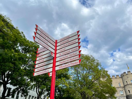 A closeup shot of a sign showing the destinations on a cloudy background in Cologne, Germany