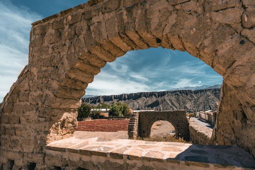 A stone arch with peppers drying in the sun in the background, in a remote place in Argentina