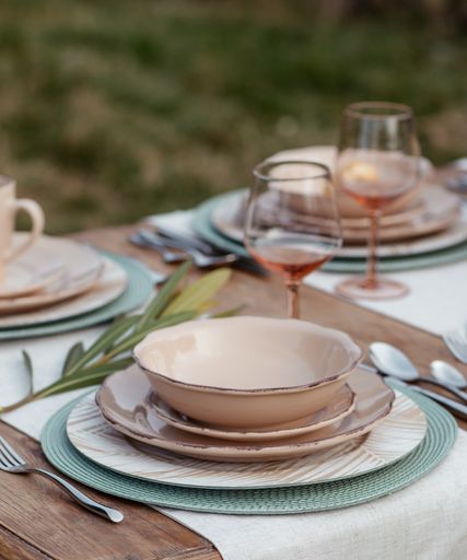 A vertical shot of empty bowls, plates, and glasses on a neatly decorated table