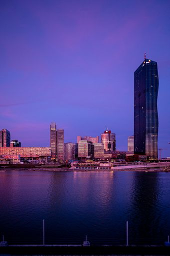 A vertical shot of DC Tower in Vienna, Austria against a purple sky at dusk