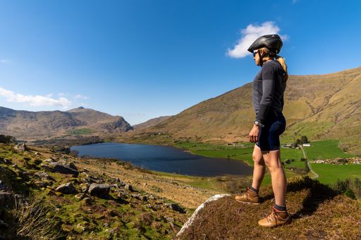 A cyclist woman looking at the mountainous landscape at Gap of Dunloe Kerry mountains