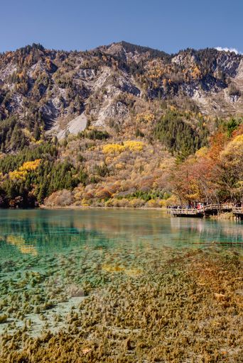 A scenic view of a lake in autumnal mountains on a sunny day