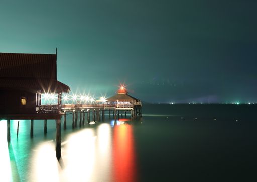 A long exposure shot of a pier on the lake at night
