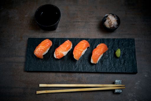 A closeup shot of sushi on a black wooden board with chopsticks