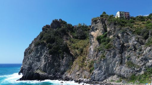 The coastal cliffs with lush greenery against the backdrop of a blue sky. Cinque Terre, Italy