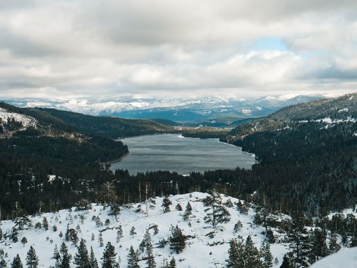 A land covered with snow overlooking the Donner Lake in Truckee, California under cloudy skies