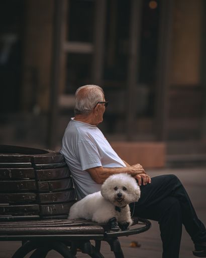 An elderly man with his dog resting on a bench in Skopje, North Macedonia