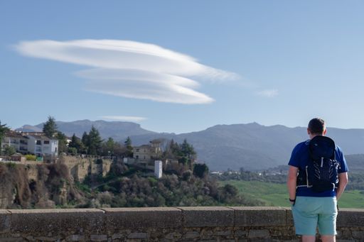 tourist seen from the back admiring an idyllic landscape of a village on a cliff and a blue sky with clouds