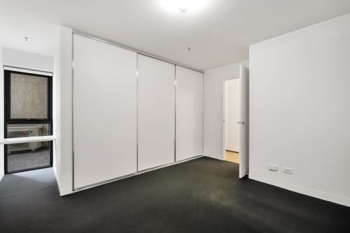 An empty bedroom with white walls and a wardrobe