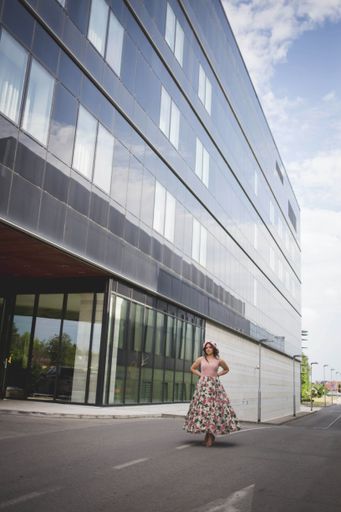 A pretty Caucasian woman with a floral skirt posing in front of a restaurant building