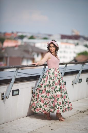 A shallow focus vertical shot of a woman standing on a roof a pink dress