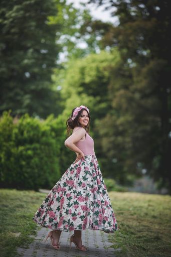 A pretty Caucasian woman with an evening dress and a floral bezel posing in the park
