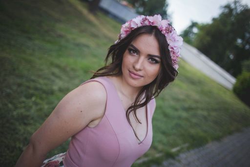 A pretty Caucasian woman with an evening dress and a floral bezel posing in the park