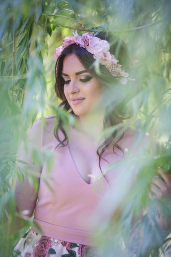 A pretty Caucasian woman with an evening dress and a floral bezel posing in the park