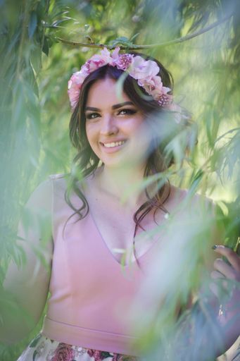 A pretty Caucasian woman with an evening dress and a floral bezel posing in the park