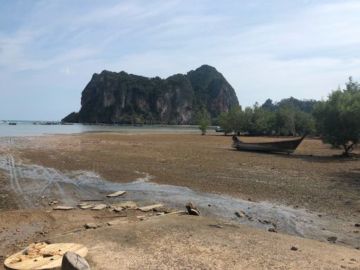 Small boat on beach by water with mountains in background
