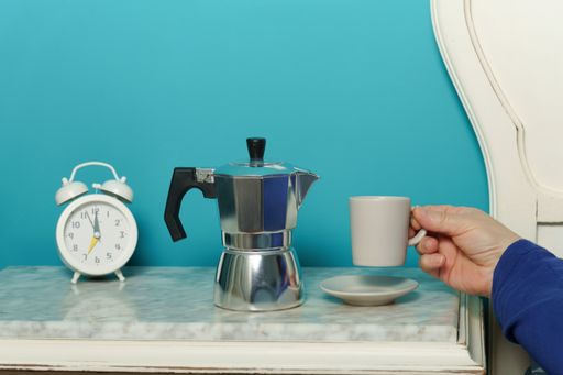 woman lying in bed having breakfast with a cup of coffee when she wakes up