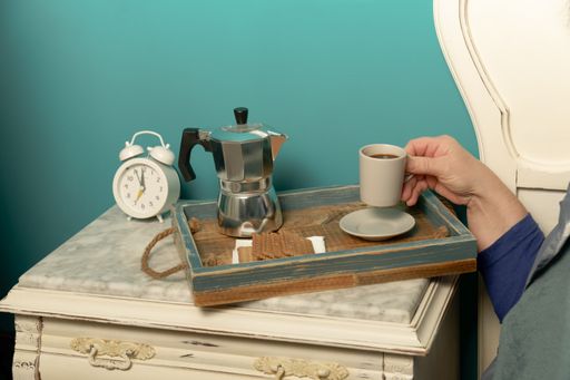 woman lying in bed having breakfast with a cup of coffee when she wakes up