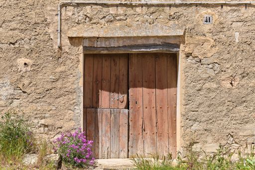 A closeup shot of a facade of an old abandoned house with an old wooden door