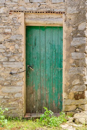 A vertical shot of a facade of an old abandoned house with an old wooden door
