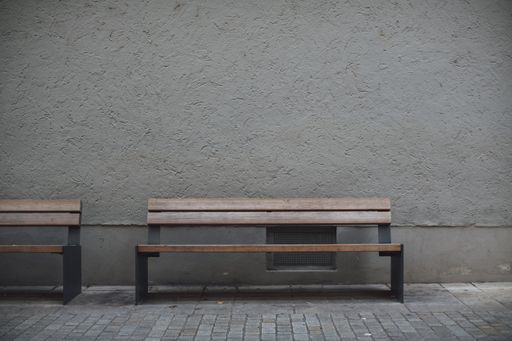 A closeup shot of wooden benches against a grey stone wall in an empty street