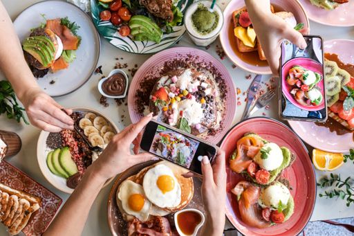 Friends taking pictures of food on the table with smartphones during brunch in restaurant