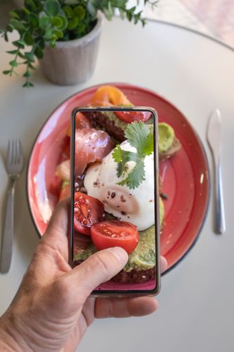 Smartphone food photography of a vegetarian lunch or brunch. Man's hands taking phone photos of food in a modern style for social networks or blogs.