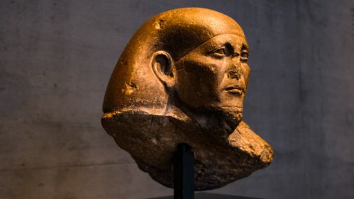A sculpture of an Egyptian deity made of stone, displayed in a museum