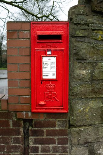Kearsley Manchester January 2024, Royal mail square red post box in the stone and brick wall with collection times printed on white notice plate UK