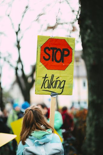A vertical shot of a female holding up a stop talking sign