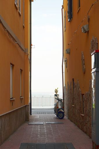 A narrow alley with a parked scooter in Giardini Naxos, Sicily, Italy.