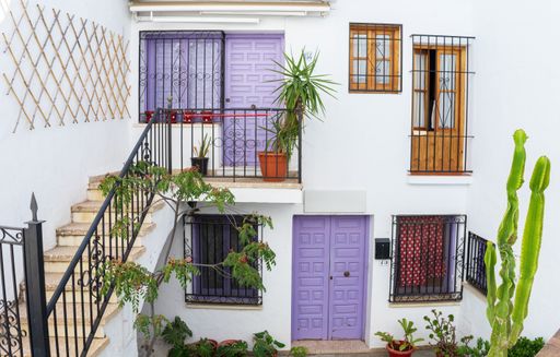 Typical facade of the white houses of Frigiliana, colorful doors decorated with plants. Houses located in one of the most beautiful villages of Spain.