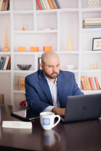 A bald businessman in formal attire, working on laptop