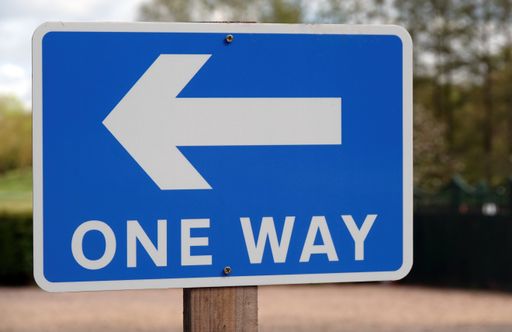 A closeup shot of a one way traffic sign in blue and white colors