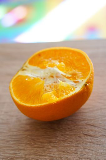 A vertical closeup shot of a fresh orange cut in half on a wooden surface