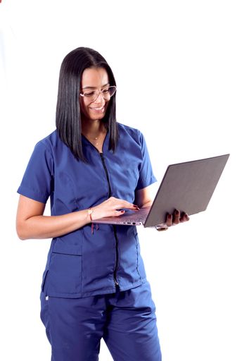A vertical shot of a cheerful young Hispanic doctor/nurse wearing glasses using a laptop