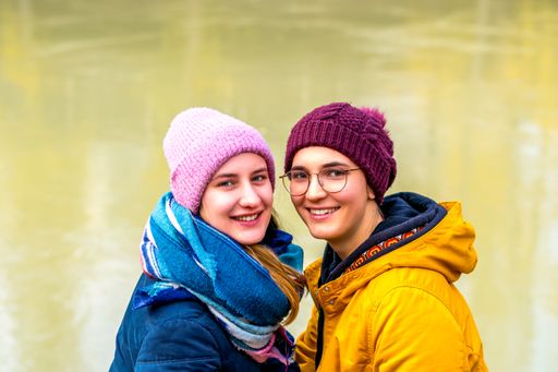 A cute lesbian couple posing by the pond in winter