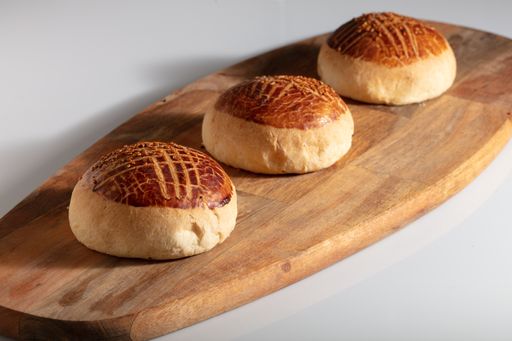 A closeup shot of freshly baked homemade buns on a chopping board on a white background