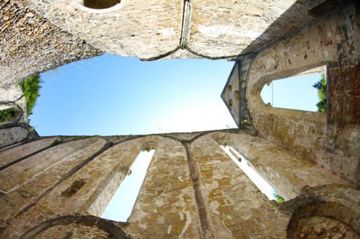 A low angle shot of an old stone wall building under a cloudless blue sky