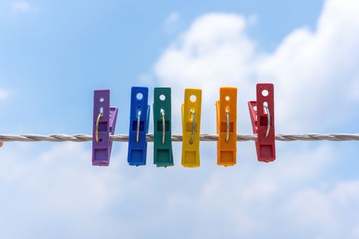 A closeup shot of multicolored plastic clothespins on an empty rope