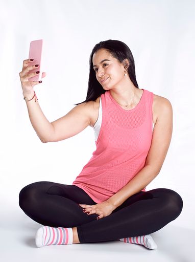 A vertical shot of a Hispanic female taking a selfie isolated on a white background