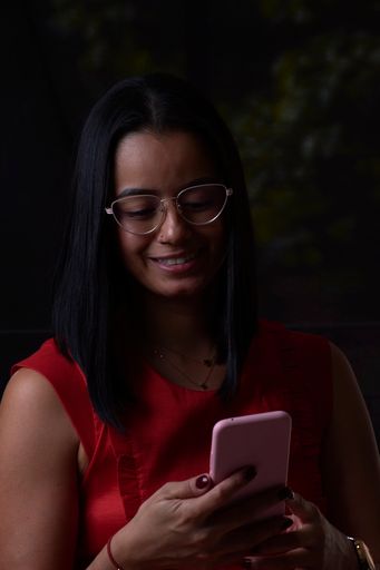 A vertical shot of a Hispanic female using her tablet isolated on a dark background