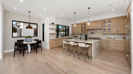 A spacious kitchen with wooden floors and white walls