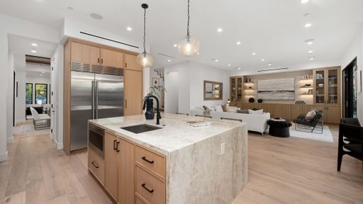 A spacious kitchen with wooden floors and white walls