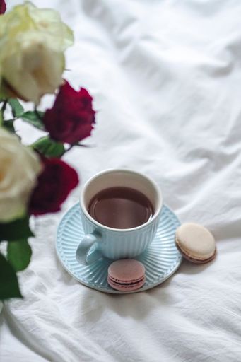 A wWhite bed with roses and a cup of coffee on white linen