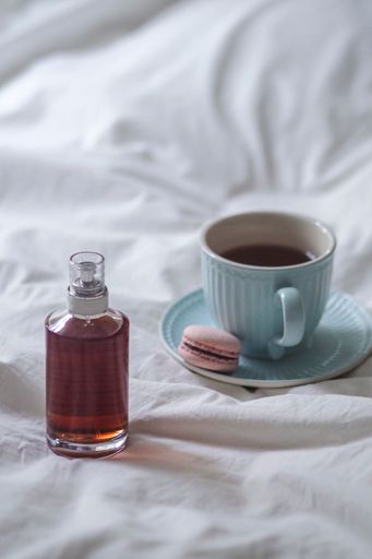 A coffee cup and syrup bottle on bed