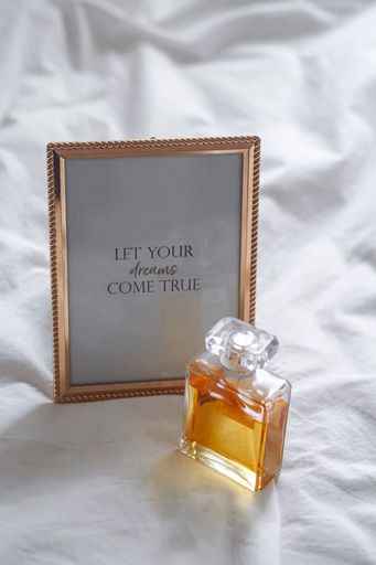 A perfume bottle and container on white bed