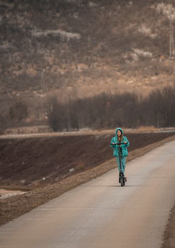 A young girl having fun with a scooter on the road