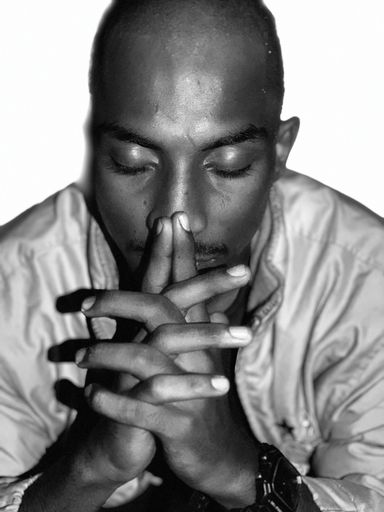 A vertical grayscale shot of a thoughtful guy from Mangalore, Inia sitting eyes closed